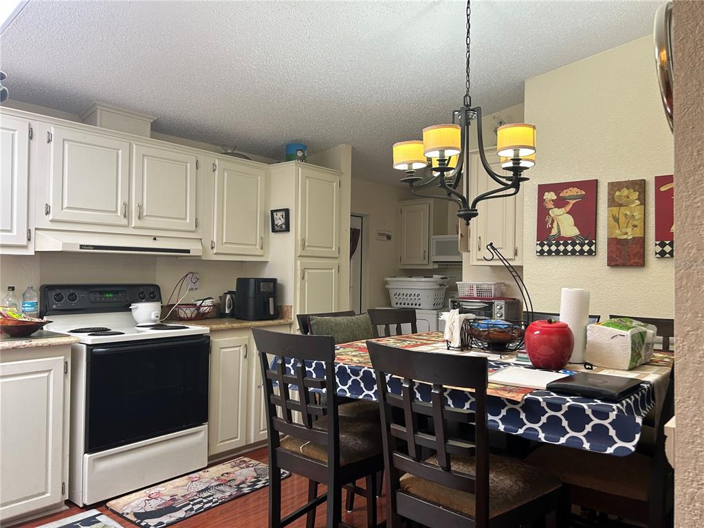 A kitchen features white cabinets, a black stove, and a dining table with four chairs — 731 POLO PARK EAST BOULEVARD, DAVENPORT, FL