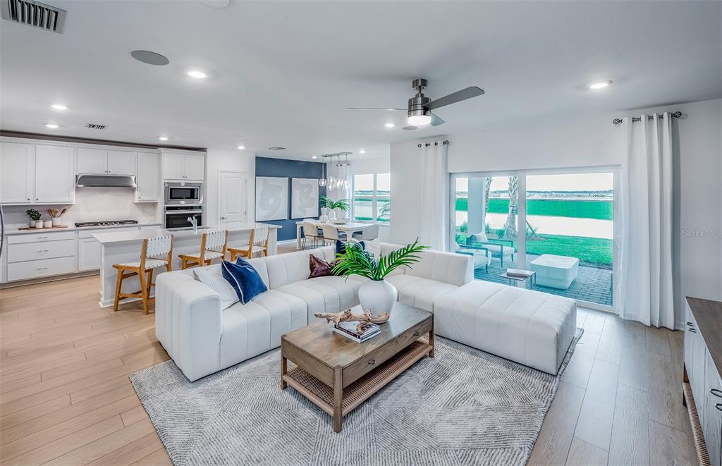 An open-concept living room and kitchen featuring white cabinetry, a sectional sofa, and sliding doors — 3948 MARBURY COURT, DAVENPORT, FL