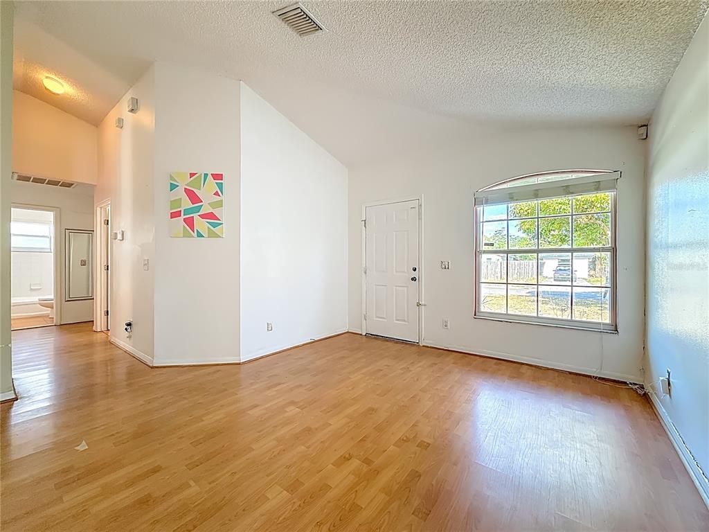 An open-concept living area features wood-look flooring, a kitchen with light cabinets, and a pantry — 1926 29TH AVENUE N, ST PETERSBURG, FL