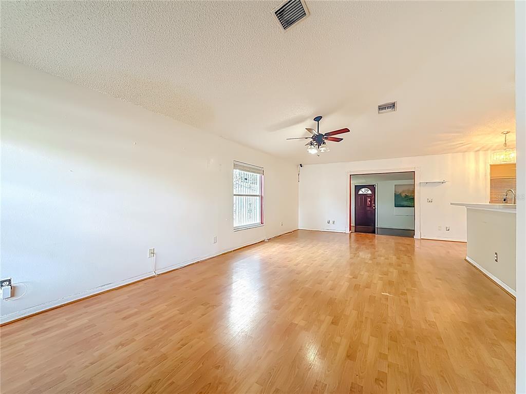 An open-concept living area features wood-look flooring, a vaulted ceiling, and an adjoining kitchen — 1926 29TH AVENUE N, ST PETERSBURG, FL