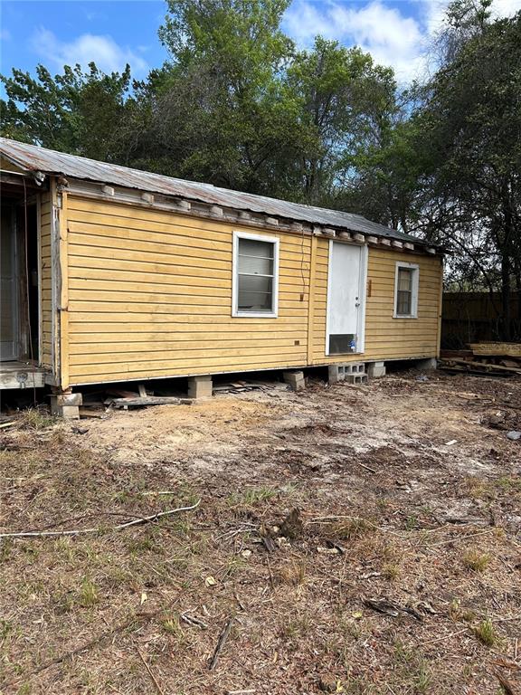 A weathered yellow house with a metal roof stands on concrete block piers — 15575 NE 234TH PLACE, FORT MC COY, FL