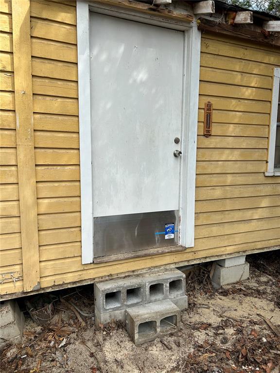 A yellow wood-sided building exterior features a white door with a metal kickplate and steps — 15575 NE 234TH PLACE, FORT MC COY, FL