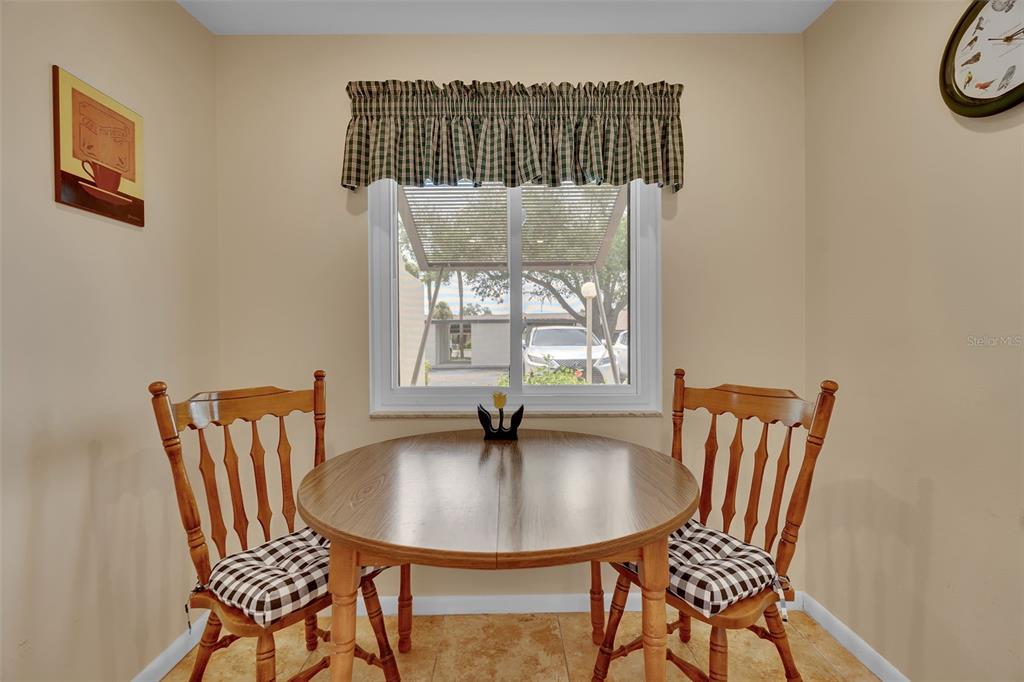 A small dining area features a round wooden table, two chairs, and a window — 4644 LONGWATER CHASE UNIT 97, SARASOTA, FL