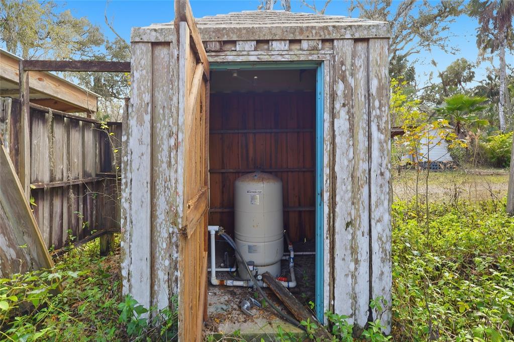 An outdoor wooden shed houses a well water pressure tank with exposed plumbing — HIGGINSON ROAD, ZEPHYRHILLS, FL