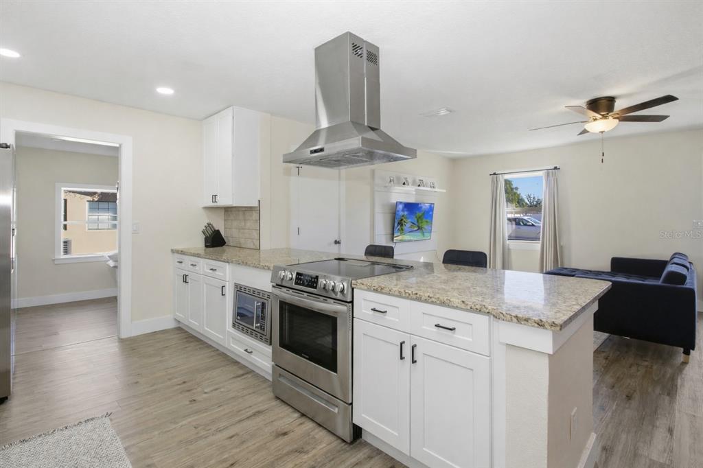 A kitchen with white cabinets, granite countertops, and a stainless steel range hood — 1509 GOLD TERRACE, DELTONA, FL