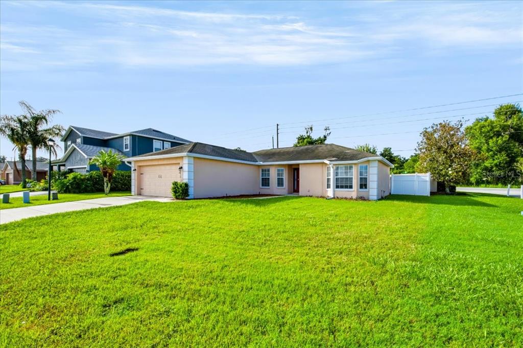 A single-story house with a tan exterior, a two-car garage, and a large front lawn — 8810 PEBBLEBROOKE DRIVE, LAKELAND, FL
