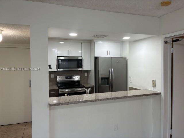 A kitchen with stainless steel appliances, white cabinets, and a granite-topped breakfast bar — 7075 NW 186th St # C507, Hialeah FL 33015, HIALEAH, FL