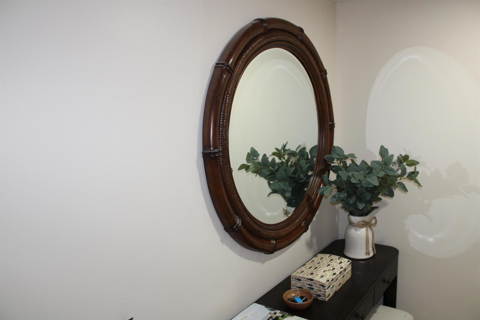 A dark wood console table with a matching oval mirror sits against a plain wall — BOYNTON BEACH, FL