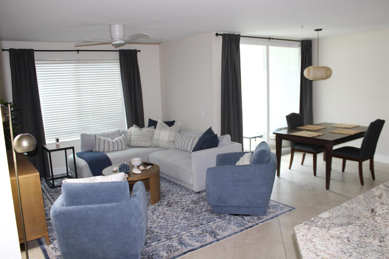 A living room with a sectional sofa, two blue armchairs, and an adjacent dining area — BOYNTON BEACH, FL
