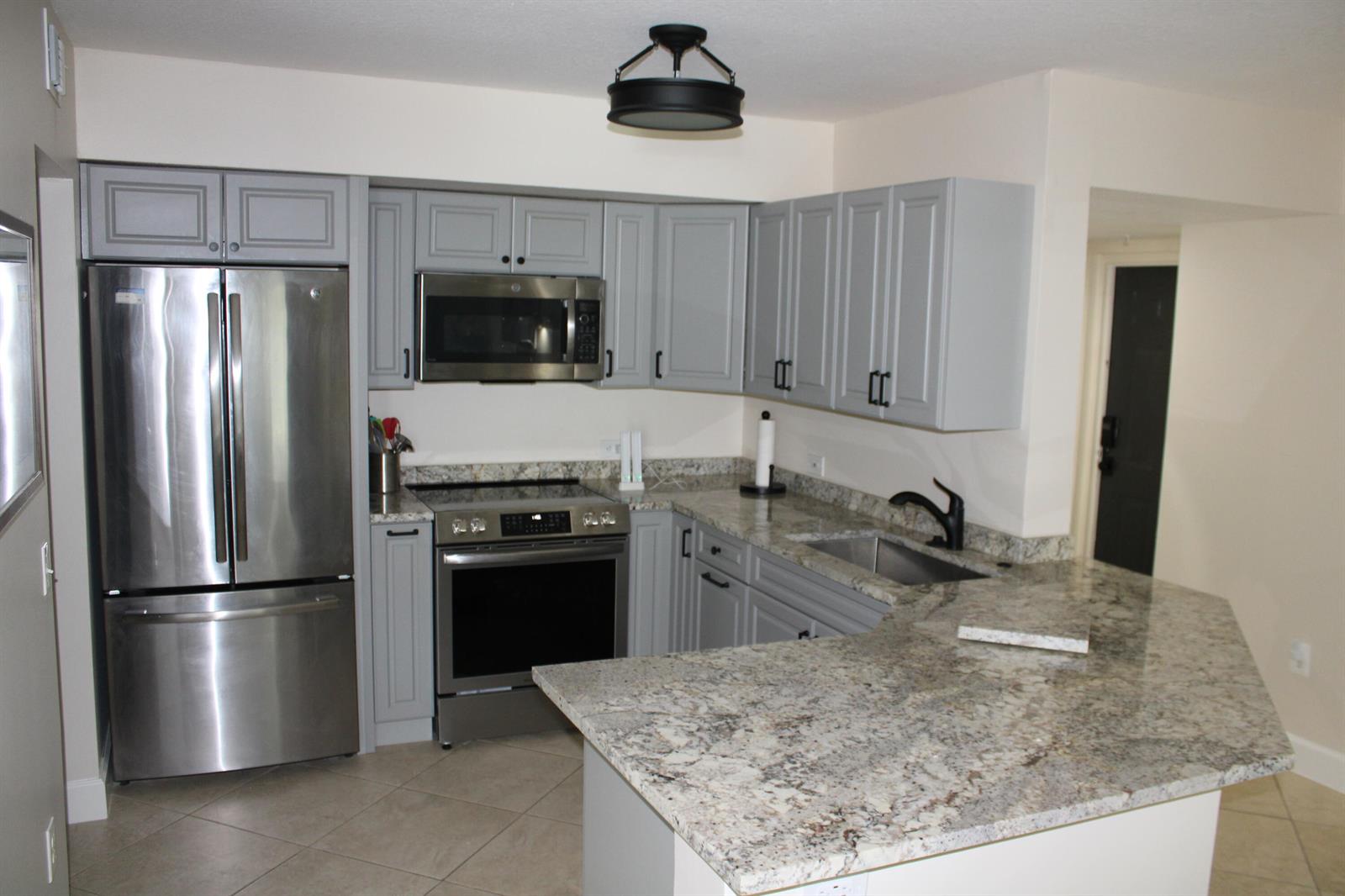 A kitchen features gray cabinets, stainless steel appliances, and granite countertops — BOYNTON BEACH, FL