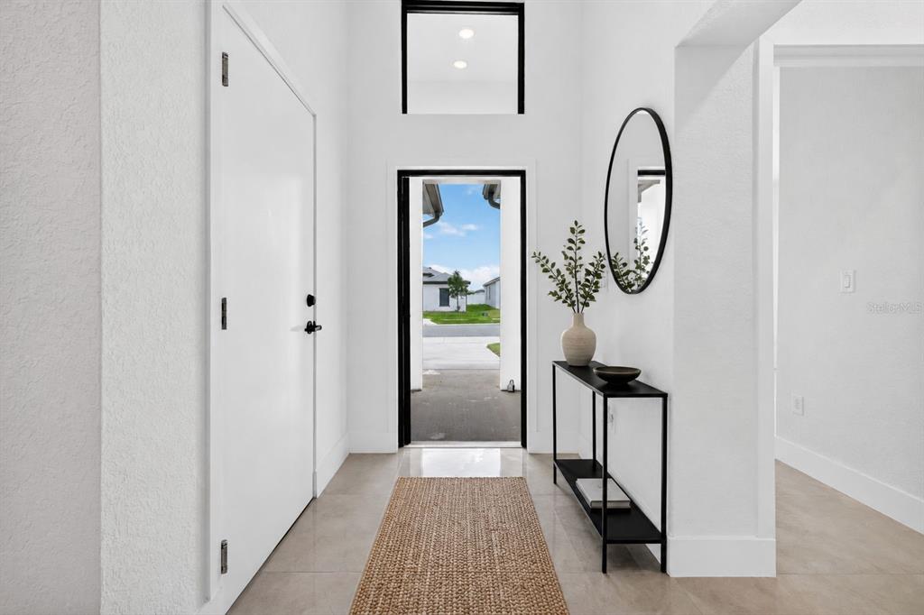 A bright entryway features a white door, a black console table, and a tall window — 6336 CHORUS DRIVE, MASCOTTE, FL