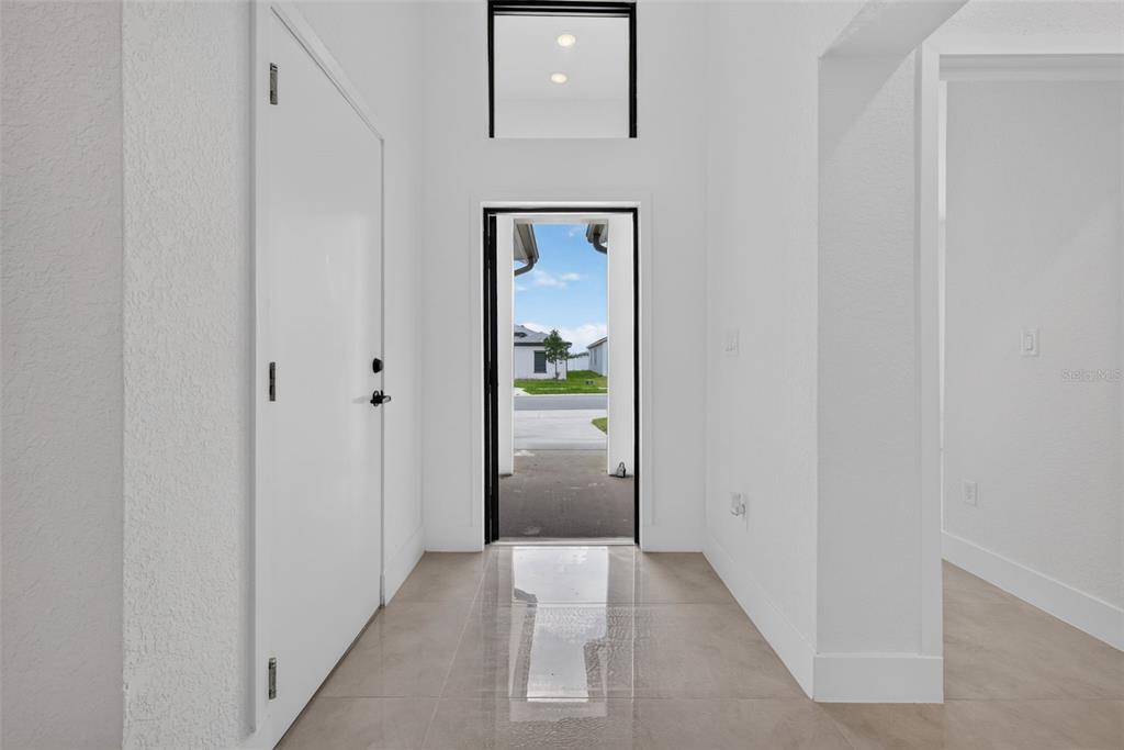 A bright entryway features white walls, tile flooring, and a doorway looking out to a street — 6336 CHORUS DRIVE, MASCOTTE, FL