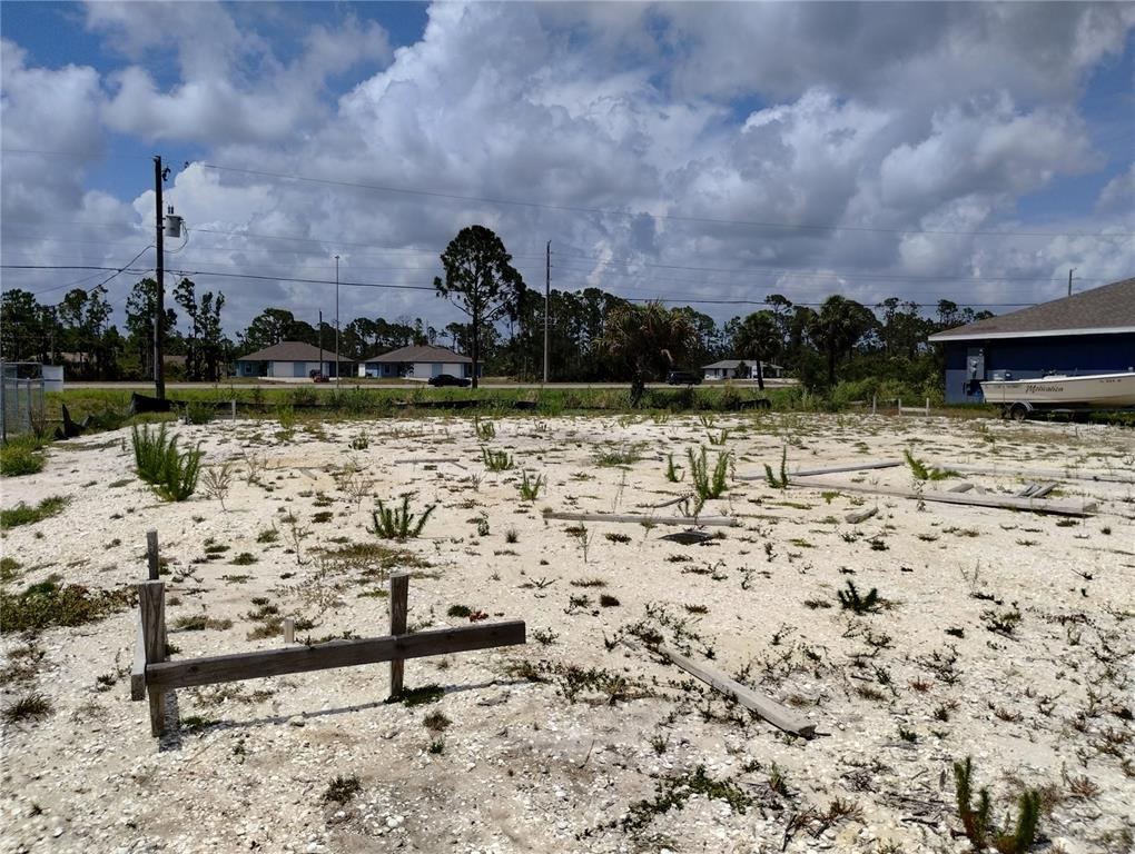 A vacant, sandy residential lot features wooden survey stakes and a boat parked nearby — 11320 POPLIN AVENUE, ENGLEWOOD, FL
