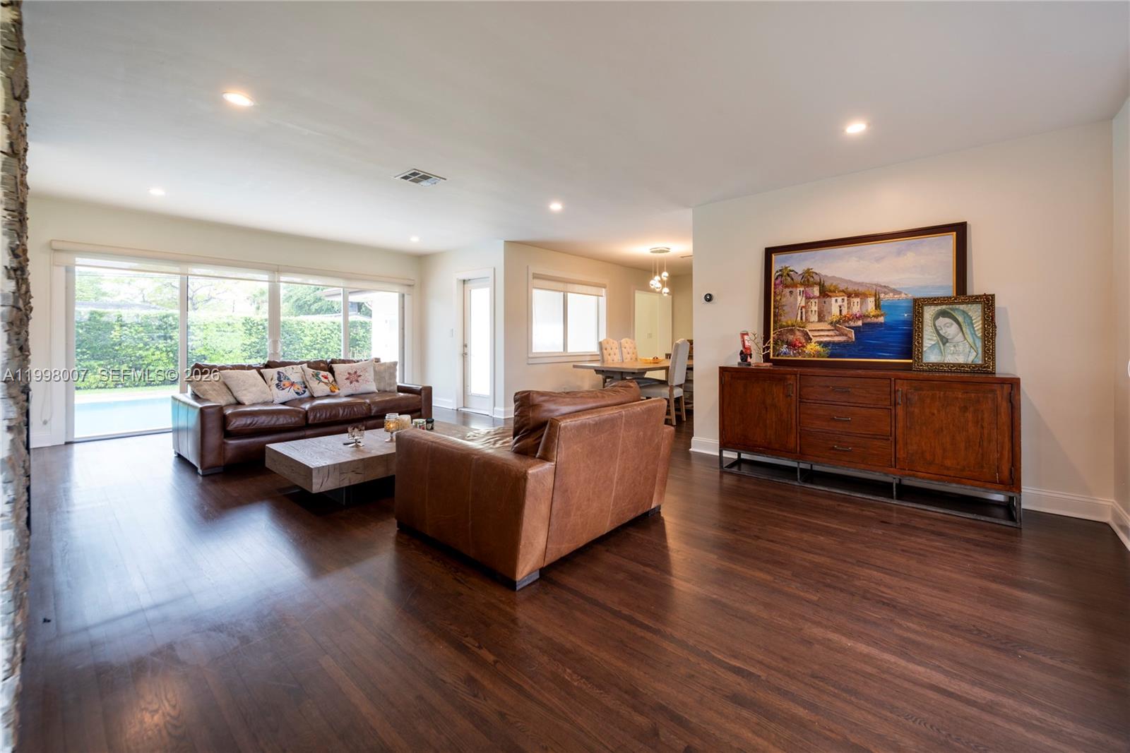 A living room features dark wood floors, leather furniture, and a large landscape painting — 3460 Buchanan St, Hollywood FL 33021, HOLLYWOOD, FL