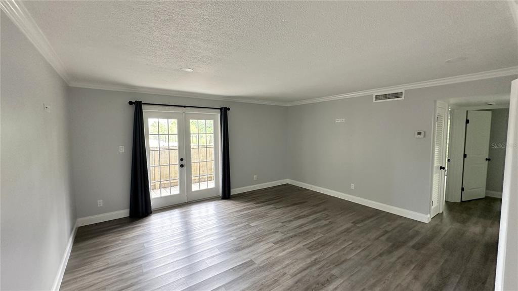 A living room with gray walls, wood-look flooring, and glass French doors leading outside — 285 WYMORE ROAD UNIT 105, ALTAMONTE SPRINGS, FL