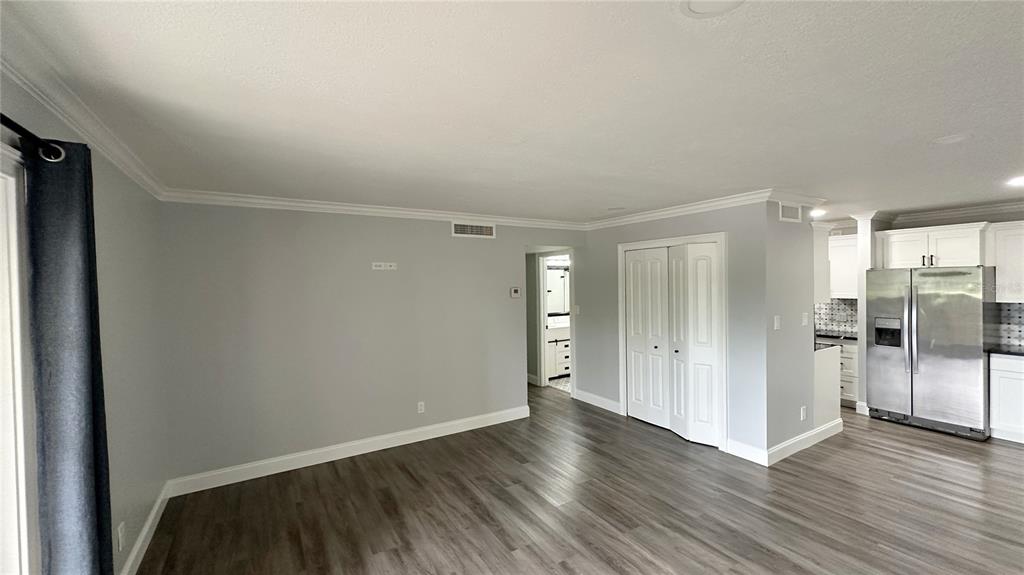 A living room with gray walls, wood-look flooring, and an adjacent kitchen with stainless appliances — 285 WYMORE ROAD UNIT 105, ALTAMONTE SPRINGS, FL