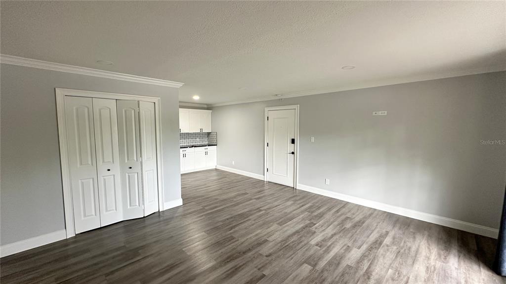 A room with gray walls, wood-look flooring, a white bifold closet, and a small kitchenette — 285 WYMORE ROAD UNIT 105, ALTAMONTE SPRINGS, FL