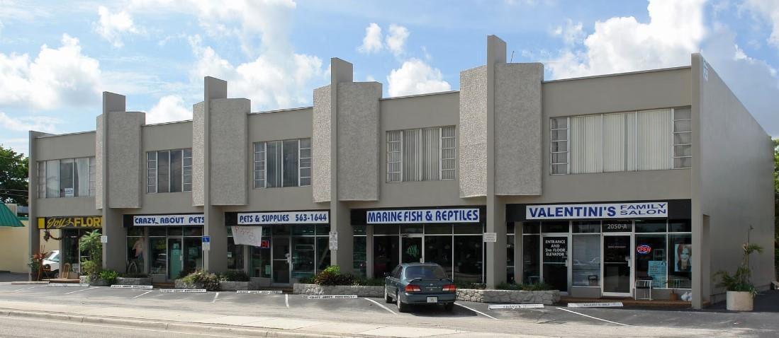A two-story commercial building with multiple storefronts and a parking lot in front — FORT LAUDERDALE, FL