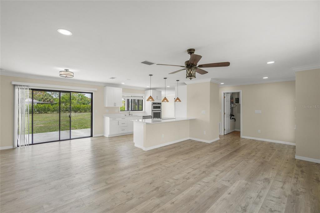 An open-concept kitchen and living area features white cabinetry, a breakfast bar, and wood-look flooring — 5050 RICHMOND TERRACE, NORTH PORT, FL