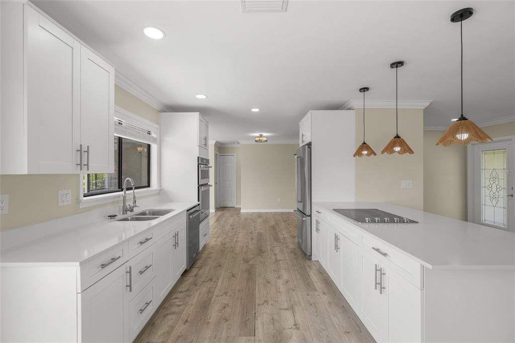A modern kitchen features white cabinetry, quartz countertops, stainless steel appliances, and wood-look flooring — 5050 RICHMOND TERRACE, NORTH PORT, FL