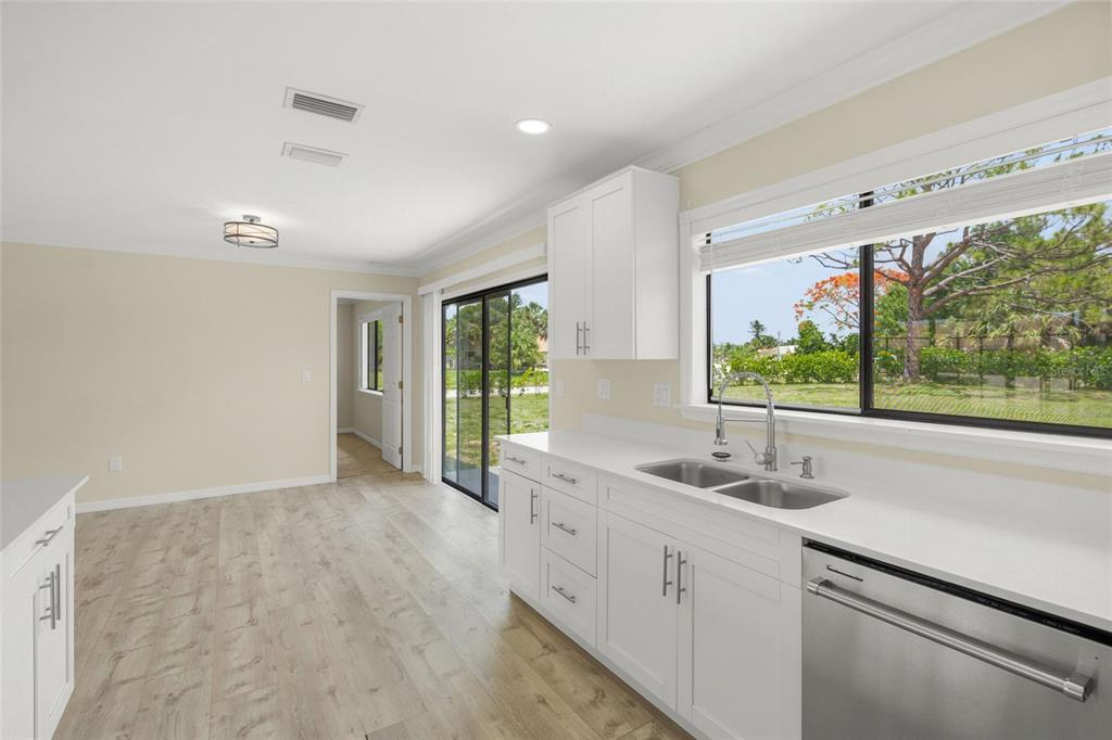 A kitchen with white cabinets, quartz countertops, stainless steel appliances, and a large window view — 5050 RICHMOND TERRACE, NORTH PORT, FL