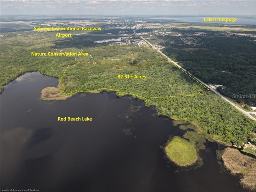 An aerial view shows a wooded 82.51-acre parcel of land bordering Red Beach Lake — 12000 US-98, SEBRING, FL