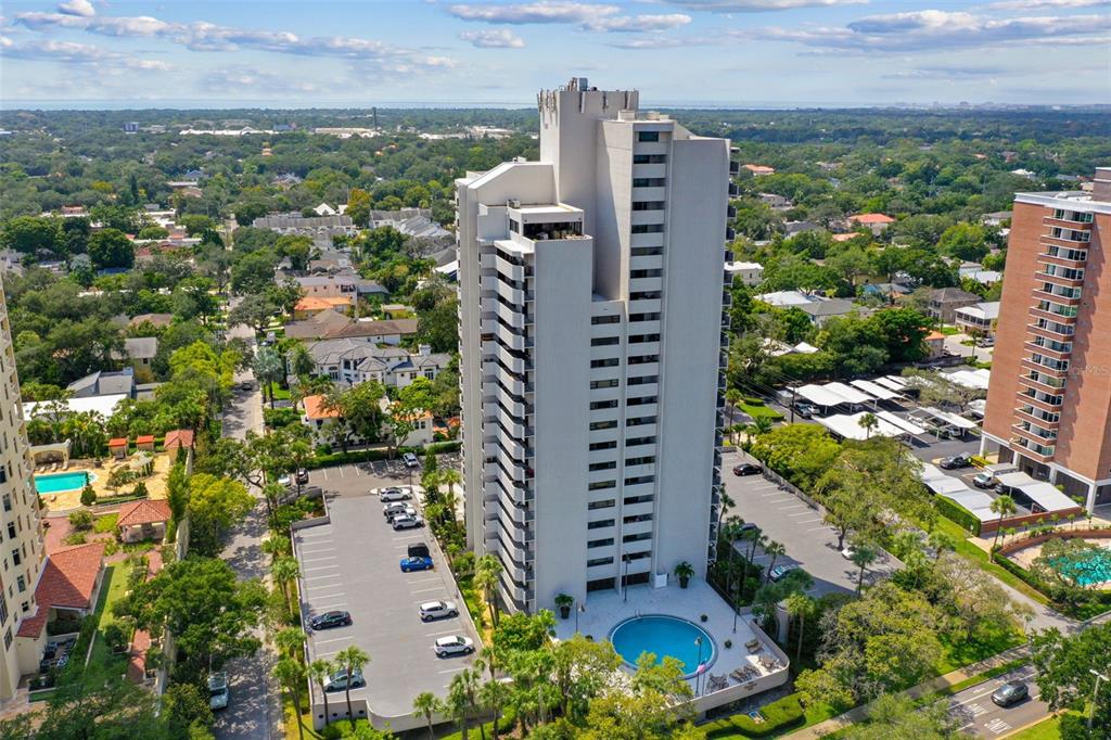 An aerial view shows a tall residential high-rise building with an adjacent parking lot and pool — 4141 BAYSHORE BOULEVARD UNIT 1106, TAMPA, FL