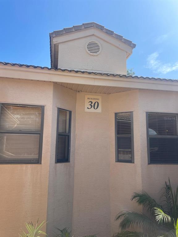 The exterior of a multi-unit residential building features stucco walls, arched entryways, and tiled roofs — 7786 SUGAR BEND DRIVE UNIT 7786, ORLANDO, FL