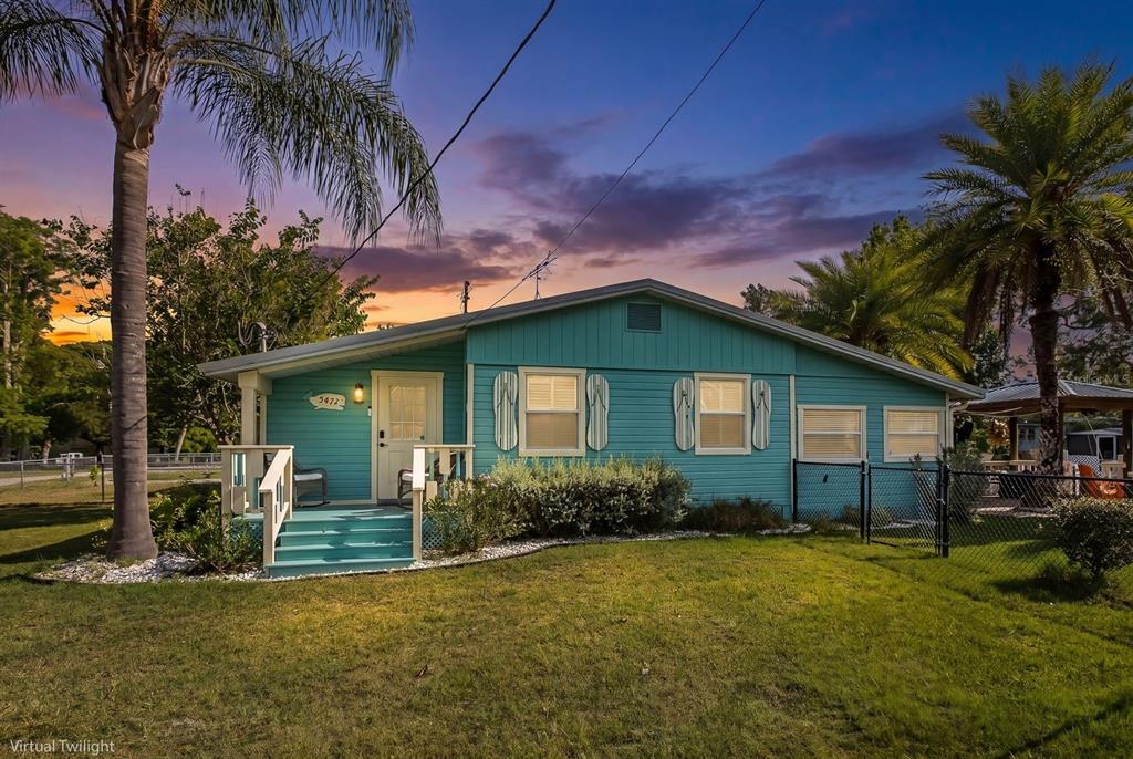A teal, single-story house with a front porch and palm trees under a sunset sky — 5473 DARLENE STREET, WEEKI WACHEE, FL
