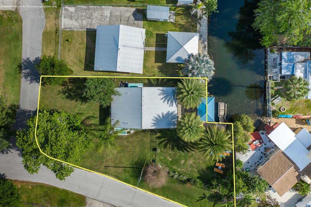 An aerial view shows a house with a metal roof situated on a waterfront lot — 5473 DARLENE STREET, WEEKI WACHEE, FL