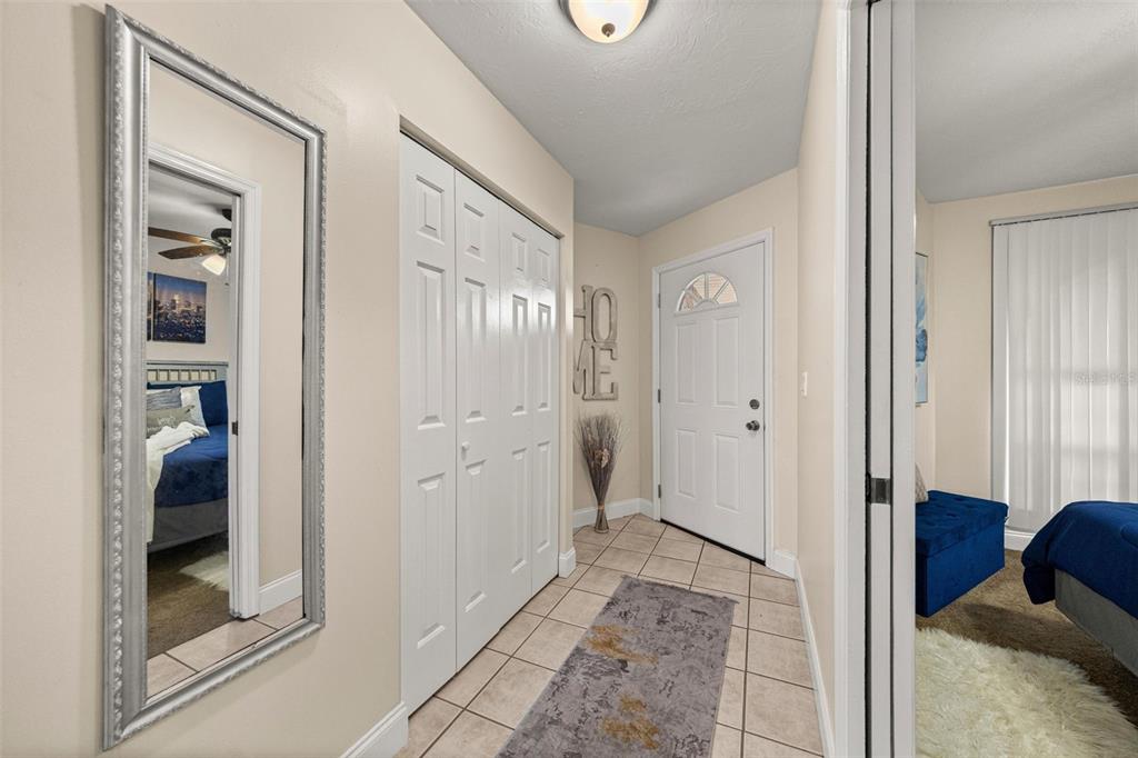 An entryway features a tiled floor, a white closet, a wall mirror, and a front door — 7799 NE 20TH COURT, OCALA, FL