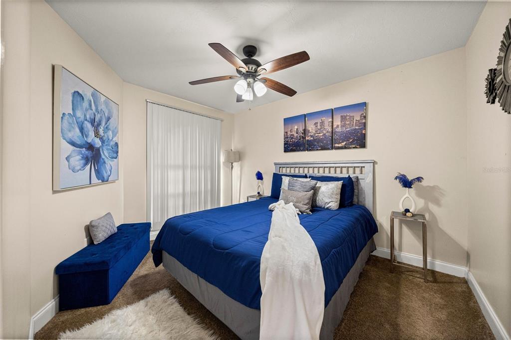 A bedroom features a blue bed, a matching storage bench, and wall art — 7799 NE 20TH COURT, OCALA, FL