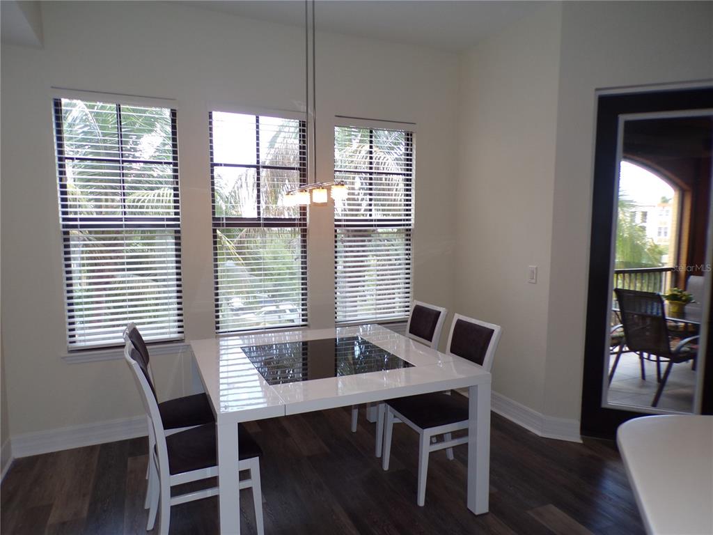 A dining area features a white table, four chairs, three windows, and a glass door — 98 VIVANTE BOULEVARD UNIT 9834, PUNTA GORDA, FL
