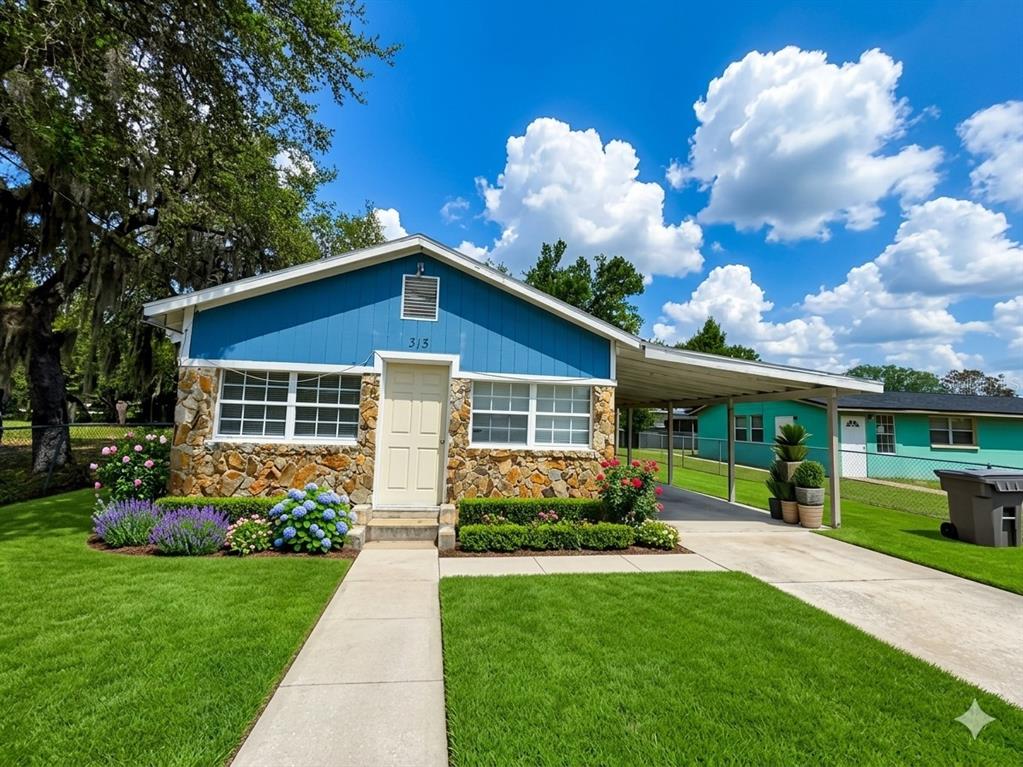 A blue house with a stone facade, a carport, and a manicured lawn — 313 E BOOKER STREET, AVON PARK, FL