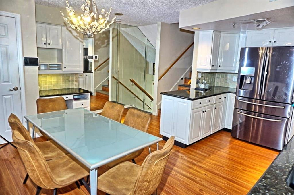 A dining area with a glass table and chairs sits adjacent to a white kitchen — 2051 VISTA DEL SOL CIRCLE UNIT 201, LUTZ, FL