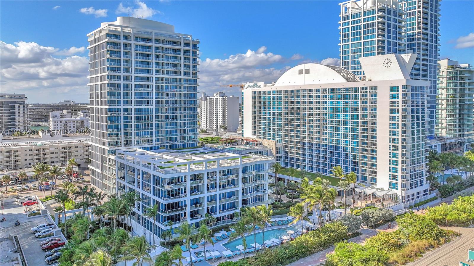 An aerial view shows multiple high-rise residential buildings with pools and landscaping near a beach — 6799 Collins Ave # 309, Miami Beach FL 33141, MIAMI BEACH, FL