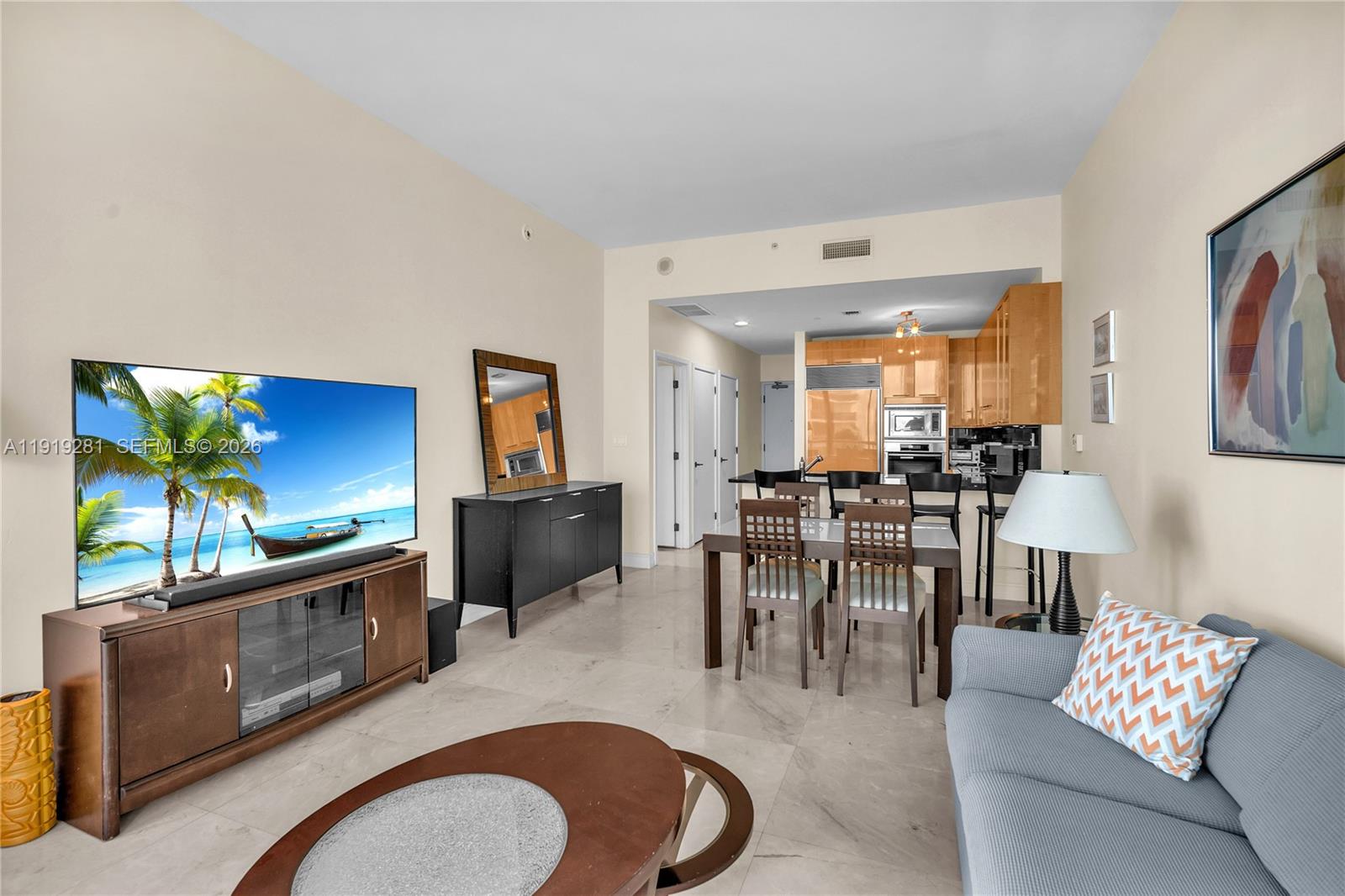A living room and kitchen area with tile floors, a television, and dining furniture — 6799 Collins Ave # 309, Miami Beach FL 33141, MIAMI BEACH, FL