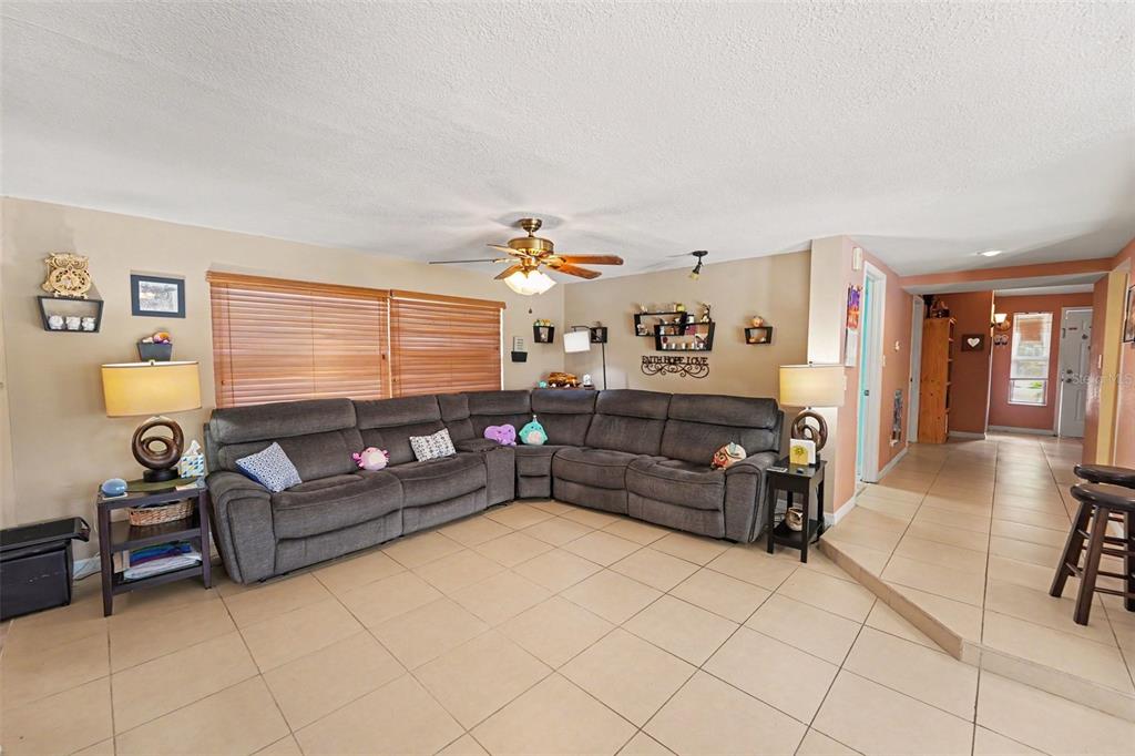 A living room features a large gray sectional sofa, tile flooring, and a ceiling fan — 9537 CRESTVIEW STREET, SEMINOLE, FL