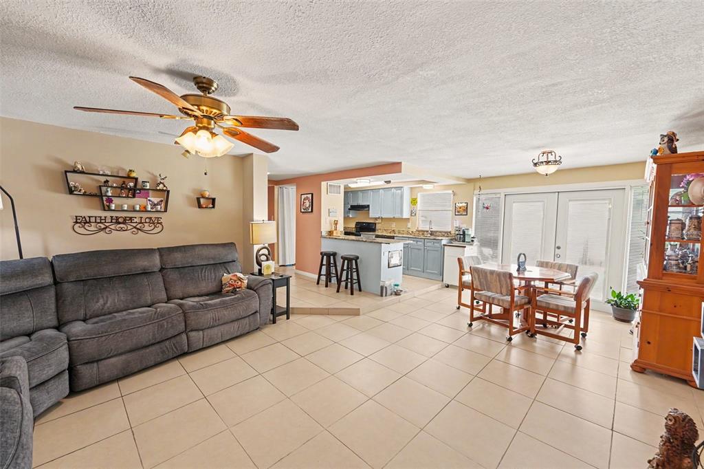 An open-concept living and dining area features tile flooring, a ceiling fan, and a kitchen — 9537 CRESTVIEW STREET, SEMINOLE, FL