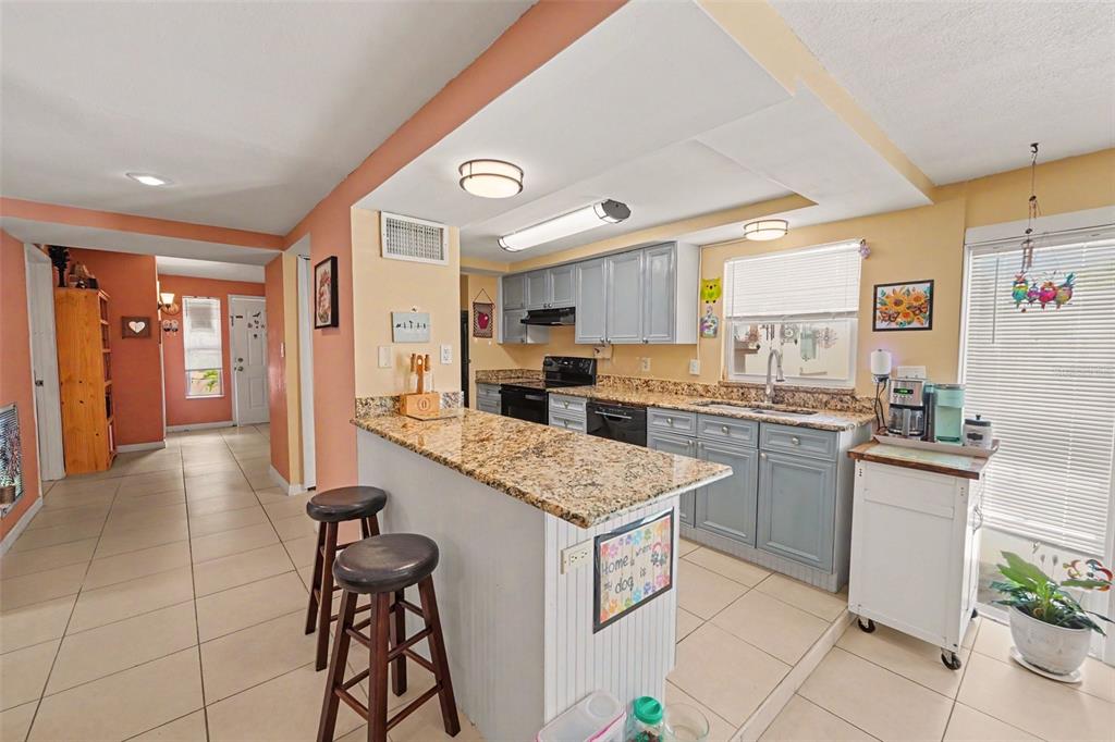A kitchen features light blue cabinets, granite countertops, a breakfast bar, and tile flooring — 9537 CRESTVIEW STREET, SEMINOLE, FL