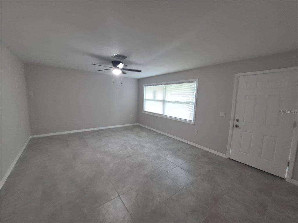 A room with gray walls, large gray floor tiles, a ceiling fan, and a white door — 15 N WASHINGTON STREET, BEVERLY HILLS, FL