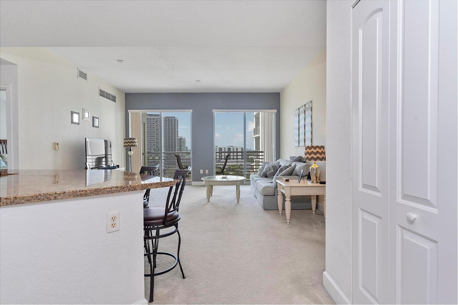 A living room with a kitchen island, carpeted floors, and a balcony with city views — 1830 Radius Drive # 1219, Hollywood FL 33020, HOLLYWOOD, FL