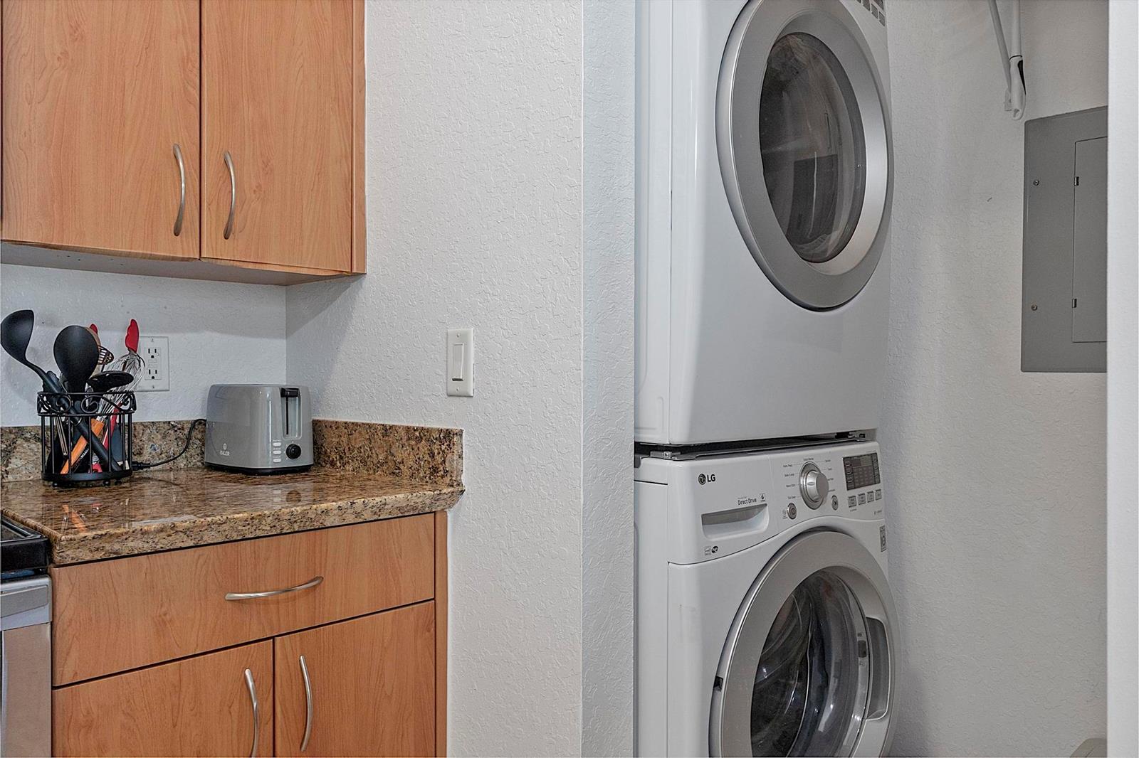 A kitchen area features wood cabinets, granite countertops, and a stacked washer and dryer unit — 1830 Radius Drive # 1219, Hollywood FL 33020, HOLLYWOOD, FL