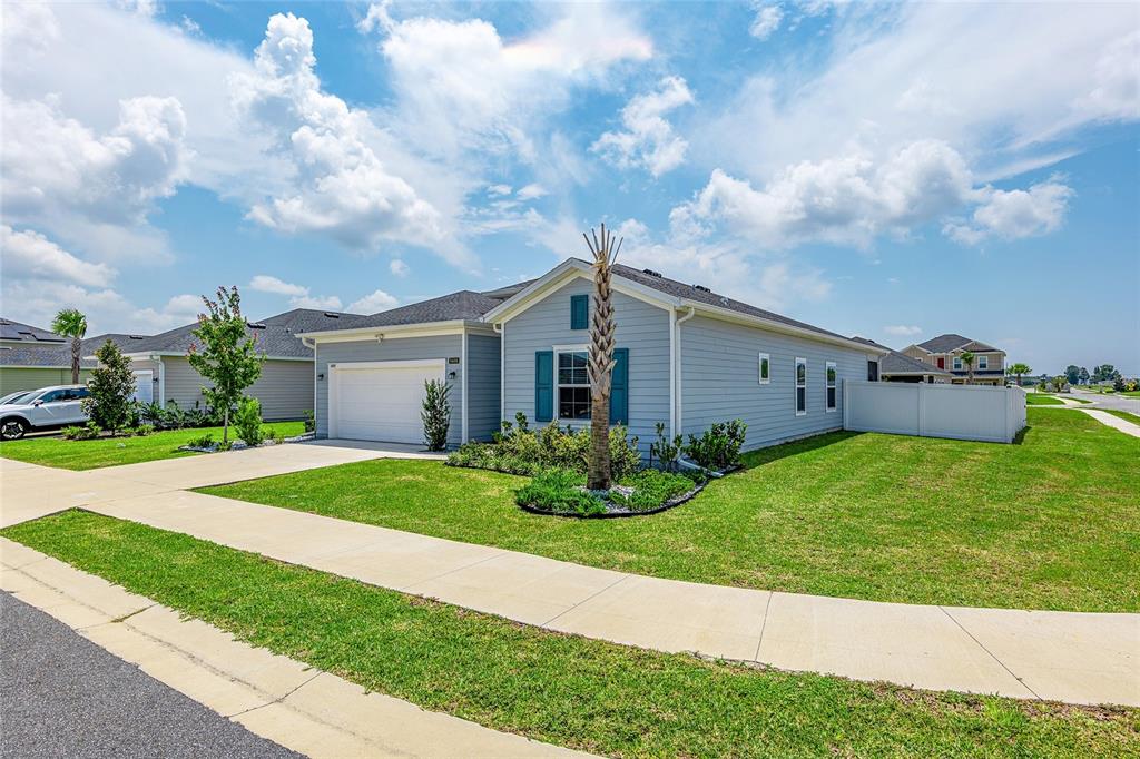 A light blue single-story house with a two-car garage and a small palm tree — 5688 SW 92ND PLACE, OCALA, FL