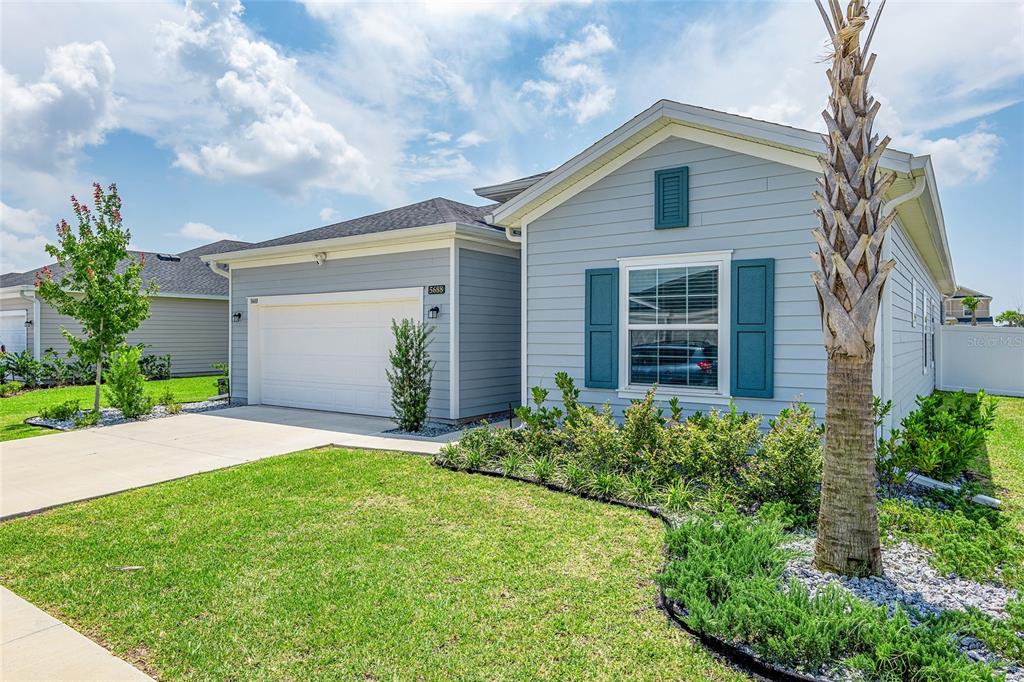A light blue single-story house with a two-car garage and a front yard palm tree — 5688 SW 92ND PLACE, OCALA, FL
