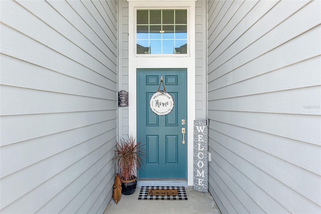 A teal front door with a transom window is flanked by light gray siding — 5688 SW 92ND PLACE, OCALA, FL