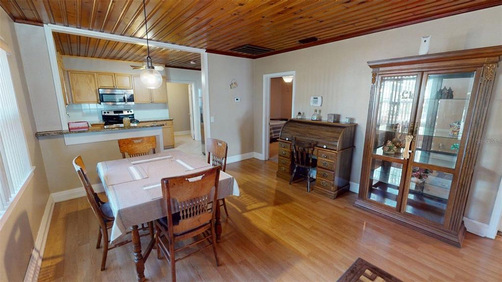 A dining room with wood-paneled ceilings, hardwood floors, a wooden table, and a china cabinet — 1405 N LAKE REEDY BOULEVARD, FROSTPROOF, FL