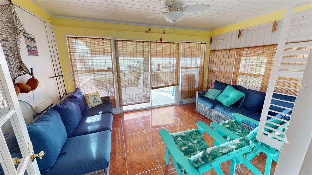 A sunroom with blue sofas, teal chairs, tiled floors, and views of the water outside — 1405 N LAKE REEDY BOULEVARD, FROSTPROOF, FL