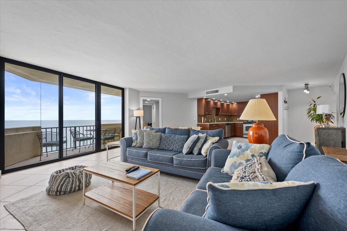 A living room with blue sofas, a coffee table, and a balcony overlooking the ocean — 2800 N Ocean Drive # 18c, Riviera Beach FL 33404, RIVIERA BEACH, FL