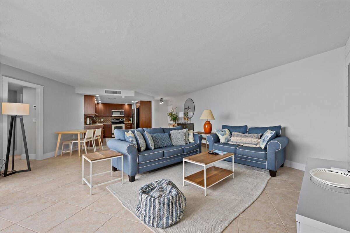 A living room with blue sofas, a wooden coffee table, and an open kitchen area — 2800 N Ocean Drive # 18c, Riviera Beach FL 33404, RIVIERA BEACH, FL